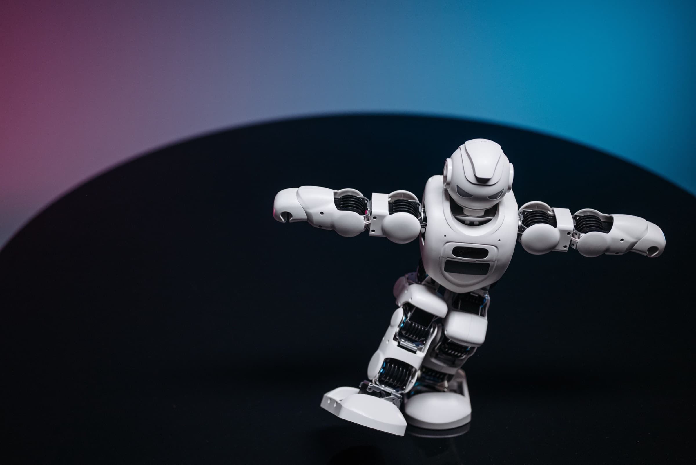 A white humanoid robot mid-stride against a blue and pink gradient — choosing between an AI chatbot and an AI agent