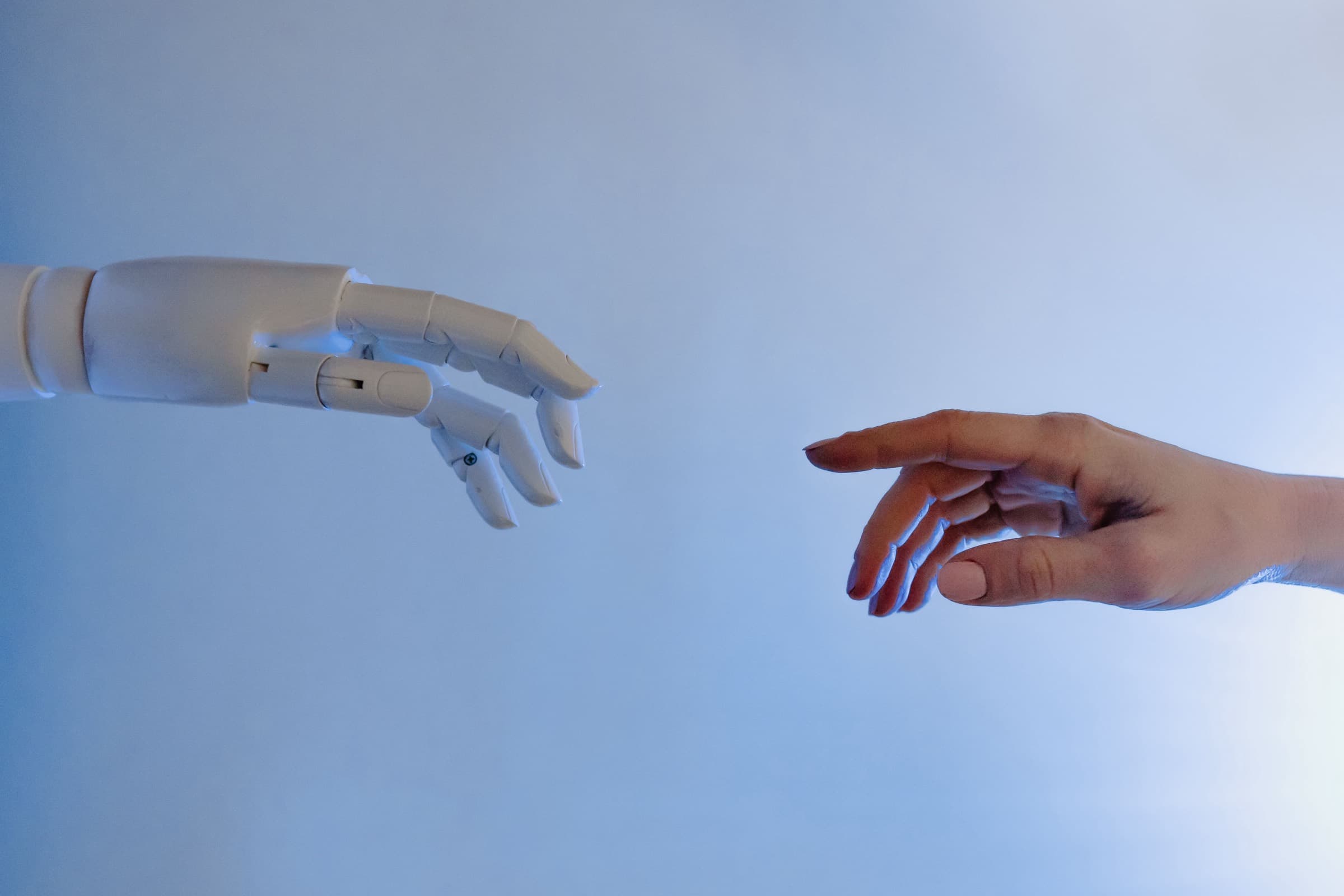 A robotic hand and a human hand reaching toward each other — custom AI automation as a partnership between software and people