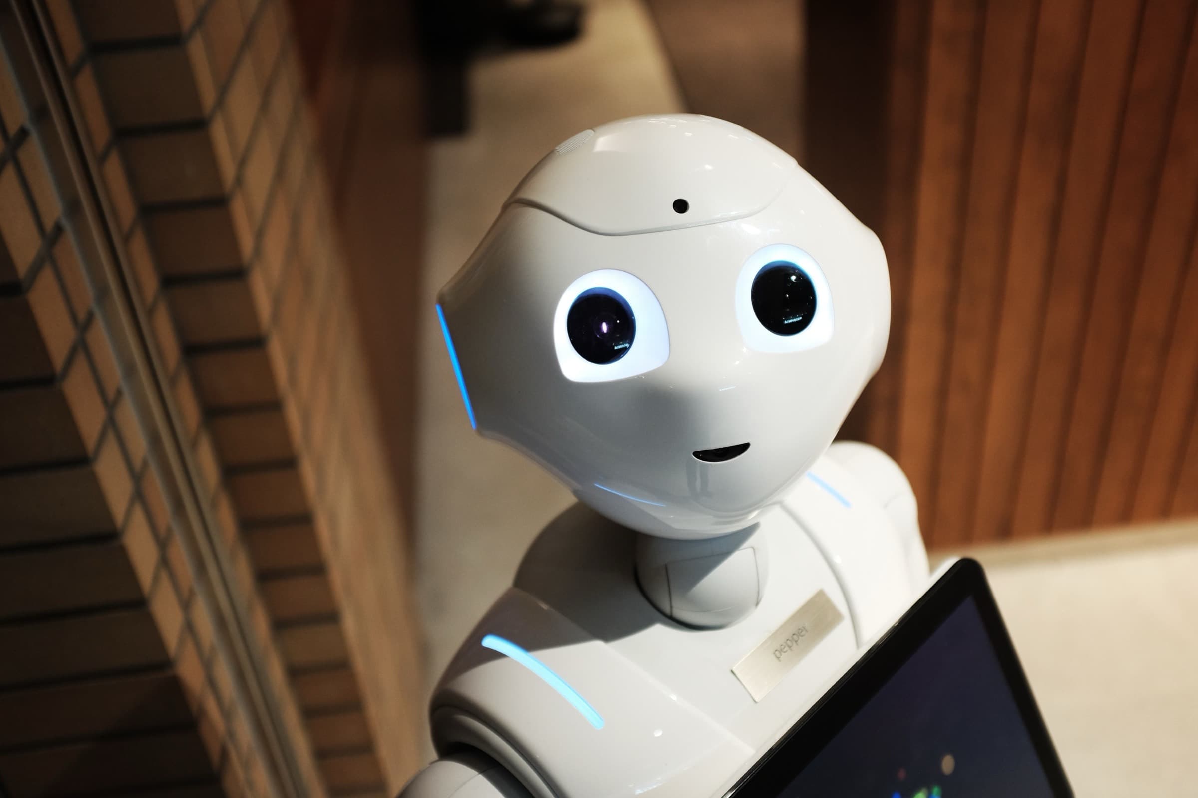 A white humanoid robot holding a tablet — AI agents as software that acts on a goal rather than a script