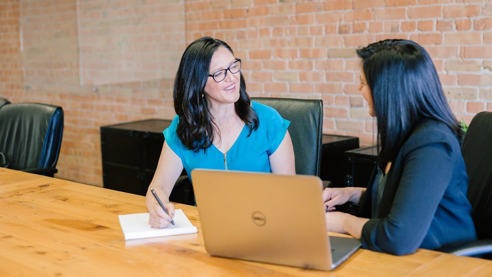 A discovery conversation across a desk — the questions asked before any design work happen to be the ones that decide whether the project succeeds