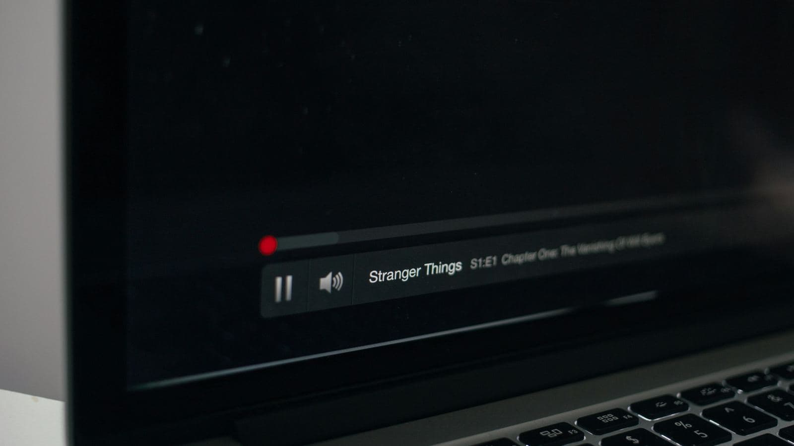 A laptop on a desk showing a paused video with its playback bar and volume control, the screen otherwise dark. Streaming video is the heaviest traffic on the internet, and almost all of it is delivered from CDN servers close to the viewer