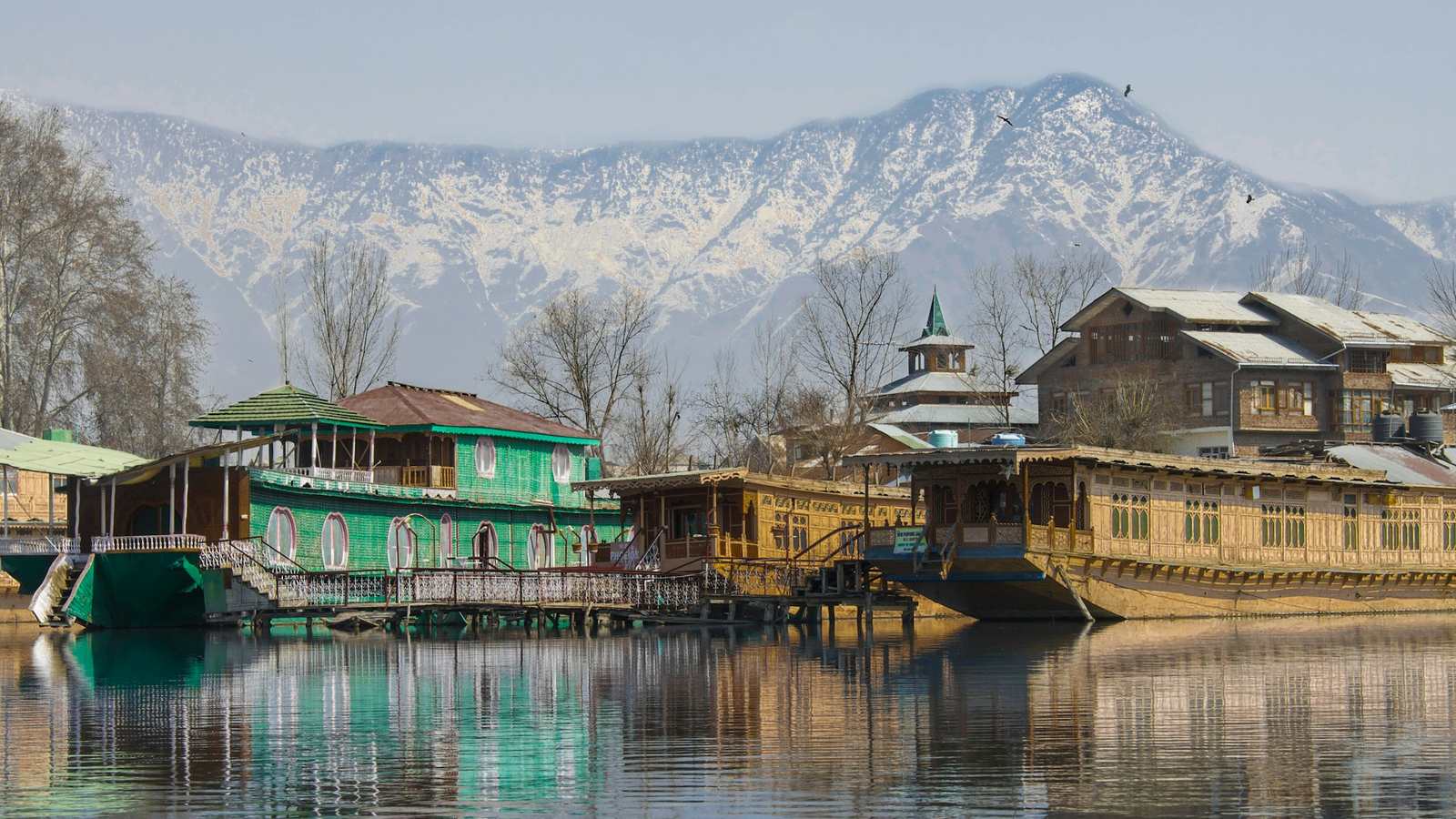 Houseboats on Dal Lake below the mountains — the valley's traffic conditions, seasons and audiences change which build actually performs