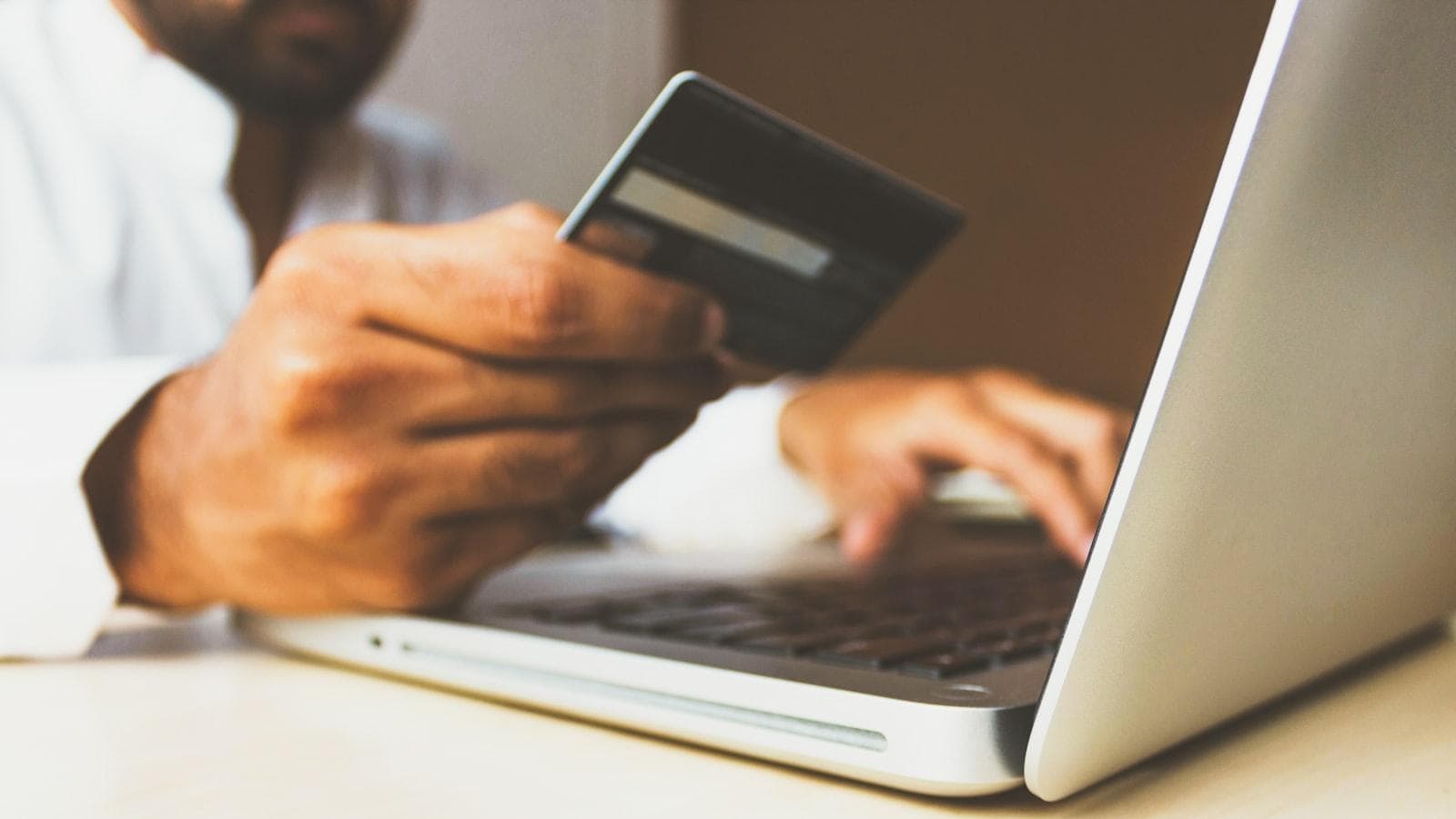 A customer holding a card at a laptop, completing an online order — the moment every ecommerce website in Kashmir is built to reach