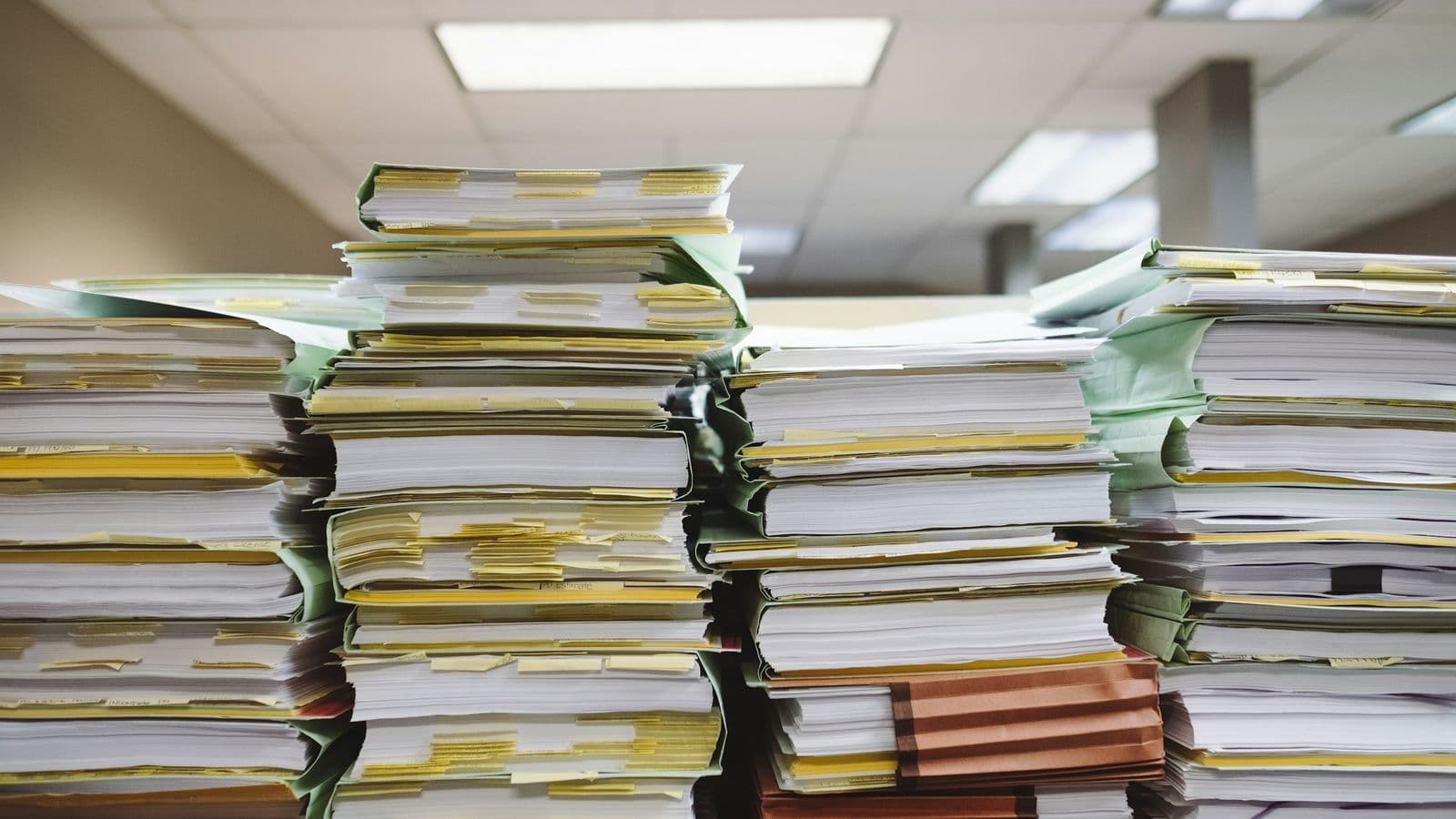 Stacks of paper files — the regulatory reality behind a clean fintech interface, and the work that decides your architecture before a single screen is designed