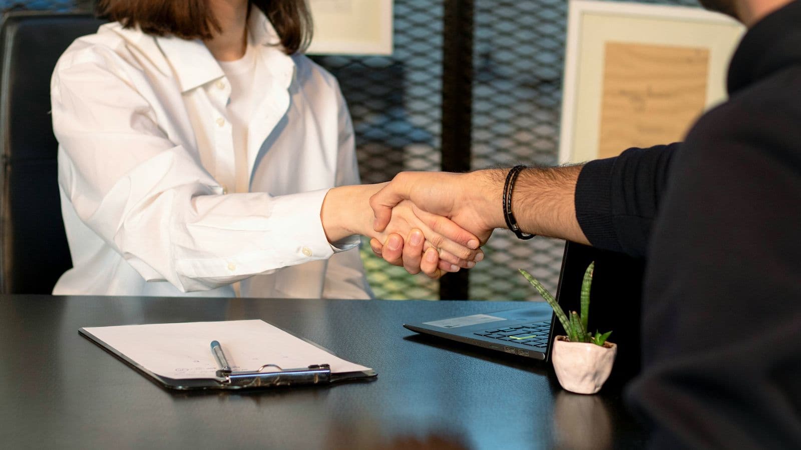 Two people closing an agreement across a desk — the best predictor of a good fintech build is a single accountable person who understands both the money and the code