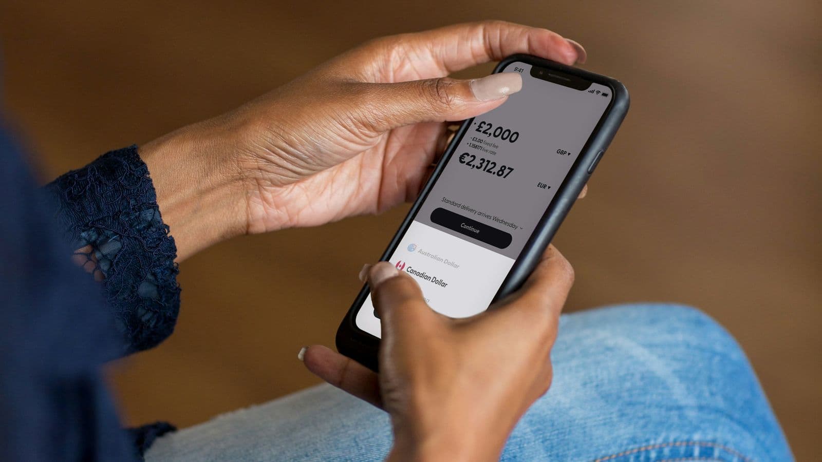 Hands on a phone showing an account balance — the surface of a fintech product is trust, and trust is an engineering property before it is a design one