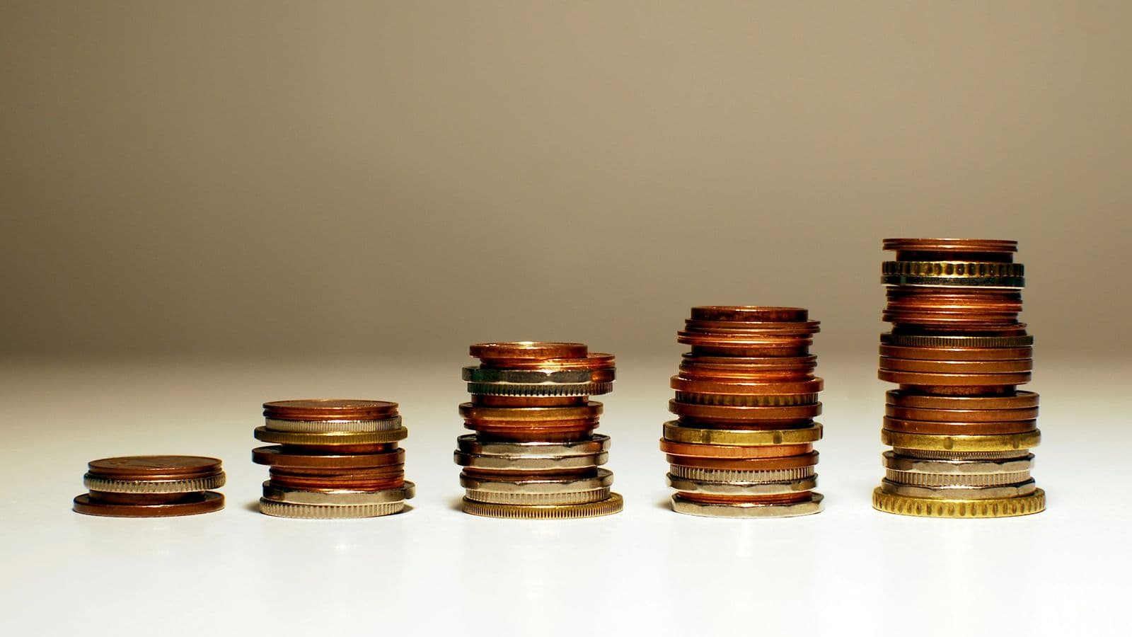 Coins stacked in rising columns. Jev's pricing comes down to never paying for output tokens you'd throw away