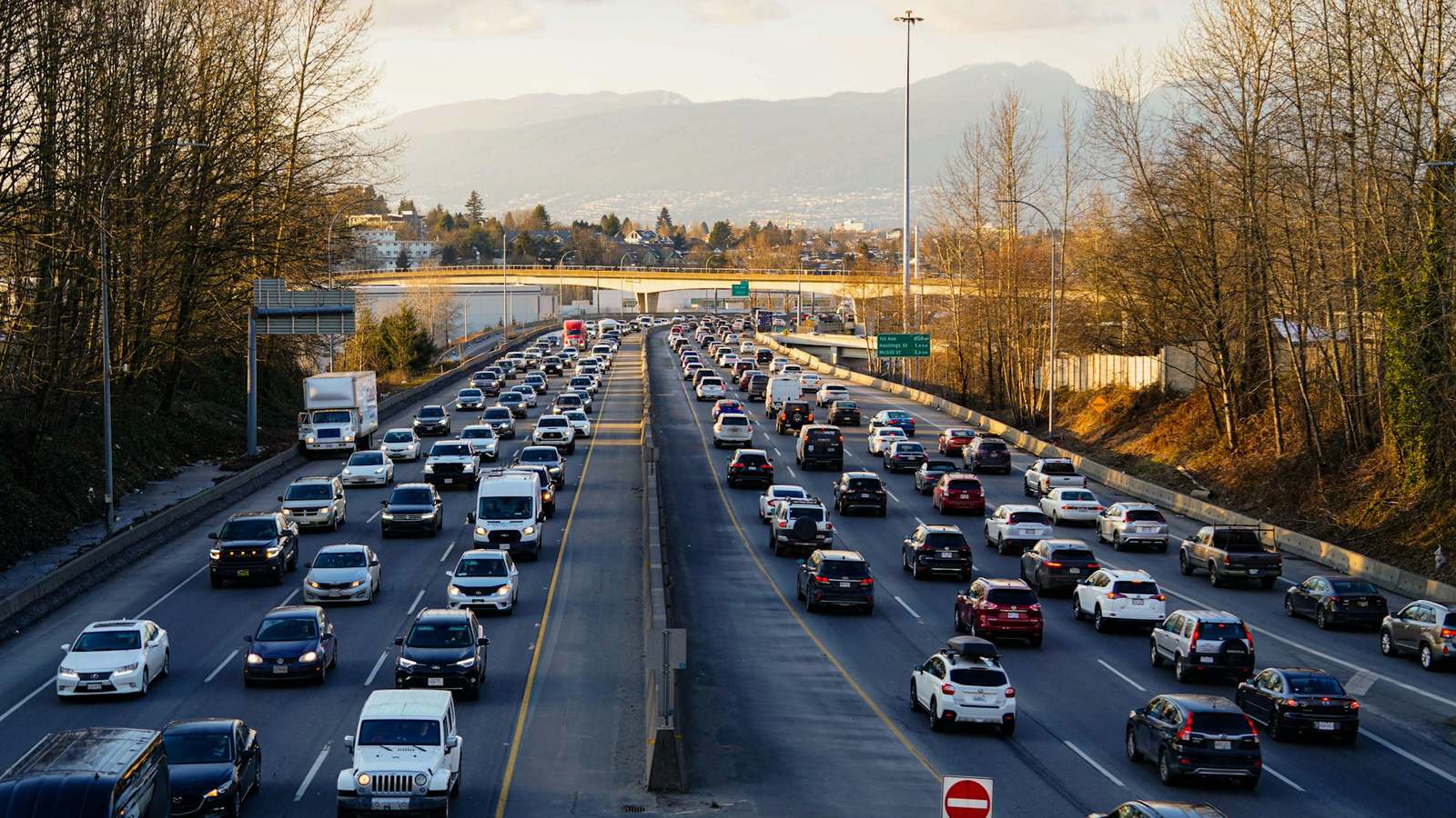 A packed multi-lane highway at sunset, both directions filled with cars heading towards a distant bridge. Traffic spikes on a website look a lot like this, and a load balancer with room to add servers is what keeps it moving