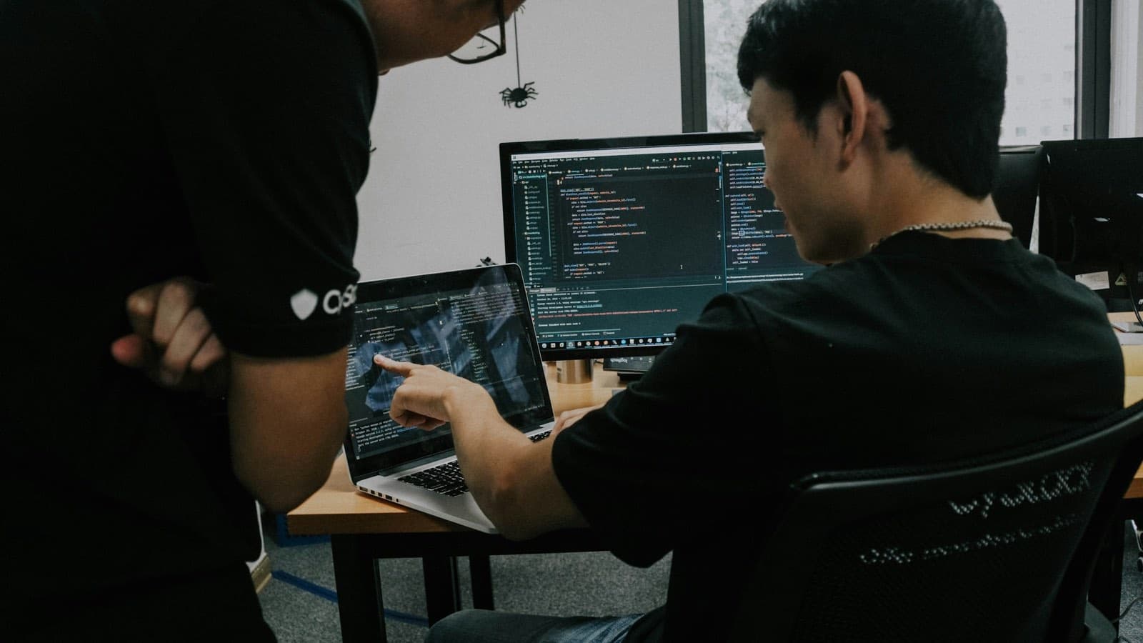 Two developers reviewing code together at a desk — the conventions above only work if someone is accountable for them after launch, not just during the build