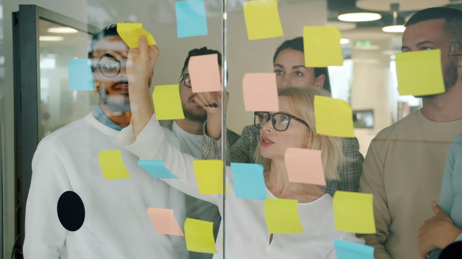 A team arranging ideas on a glass wall — architecture is mostly a set of agreements, which is why the conventions have to be written down somewhere a new developer will actually find them