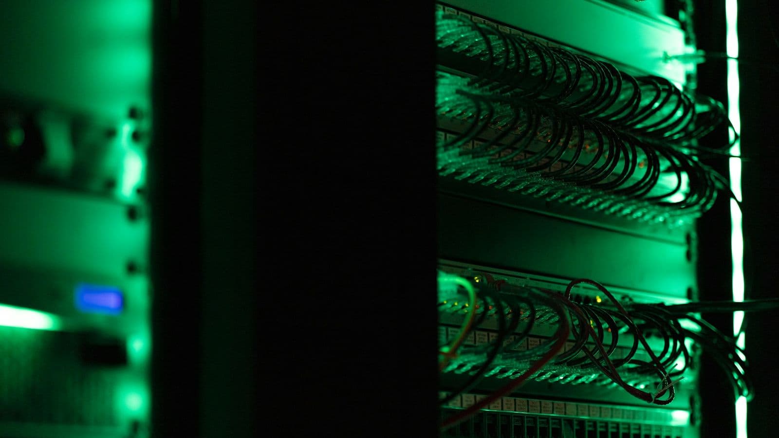 A server rack in a dark room lit by green status lights, with bundles of network cables running down its side. Where your site is hosted, and how that server is set up, decides how quickly the very first byte reaches a visitor
