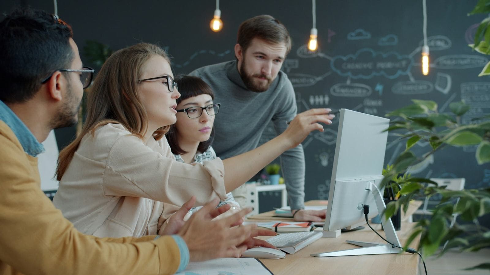 A team gathered around a monitor planning together. The right architecture for your product starts with an honest conversation about what it actually needs to do