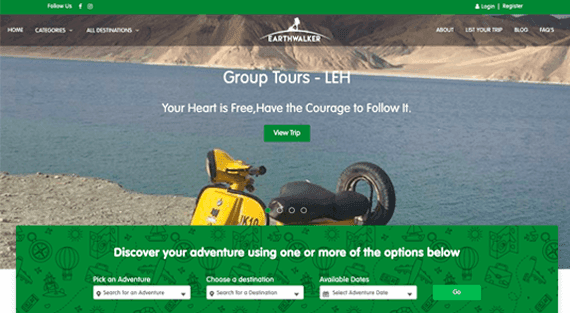 EarthWalker homepage with a “Group Tours - Leh” hero showing a yellow scooter beside a Ladakh lake, above a green search bar to pick an adventure, destination and available dates